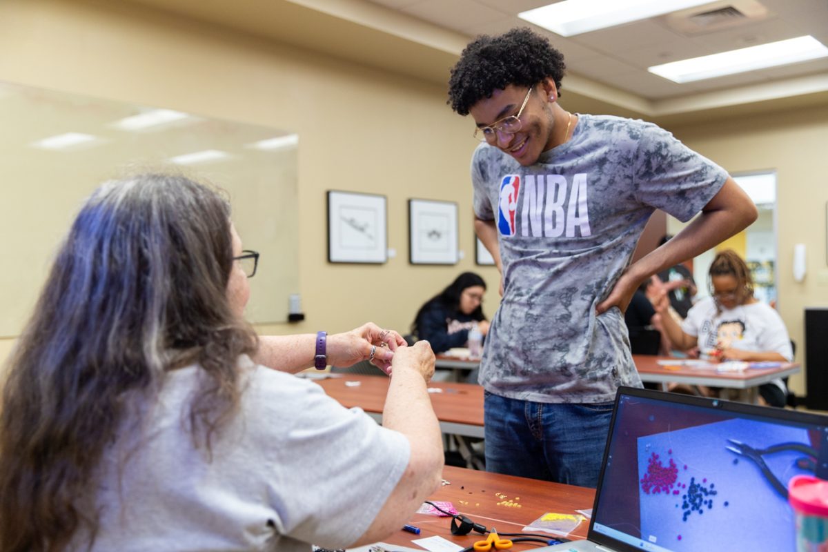 Beadworker Michelle Conine helps Araylius Coronado tie off his spiral stitch bracelet during the beadworking class on May 1. The event was one of four collaborative beadworking sessions hosted by the Indigenous Student Collective and the Office of Student Engagement & Belonging.